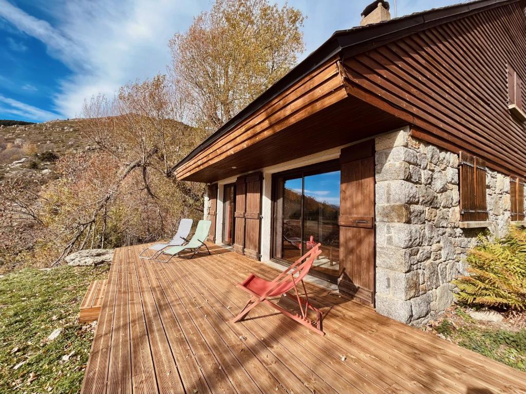 a wooden deck with two chairs on top of a house at La bergerie d'Egat: Chalet authentique avec vue in Égat
