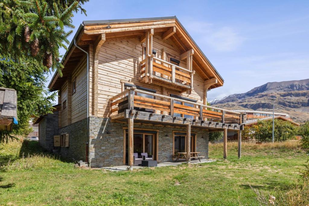 a house with a wrap around deck on the side of it at Chalet Sherpa - Welkeys in LʼHuez