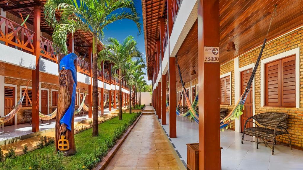 a hallway of a building with hammocks and palm trees at Jeri Hotel Group in Jericoacoara