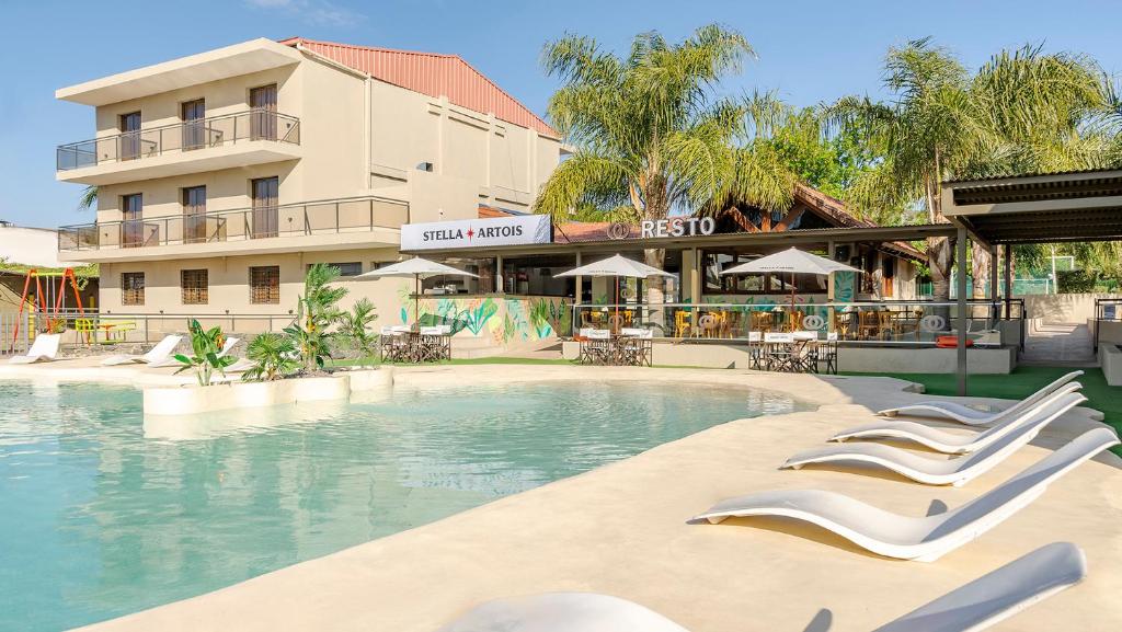 a swimming pool with lounge chairs in front of a hotel at Wooden Hotel in Villa Carlos Paz