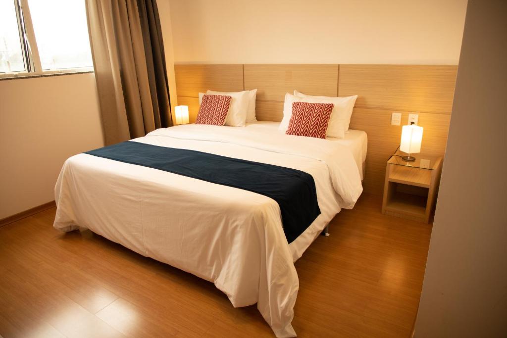 1 dormitorio con 1 cama grande con sábanas y almohadas blancas en Hotel Franco en Dionísio Cerqueira