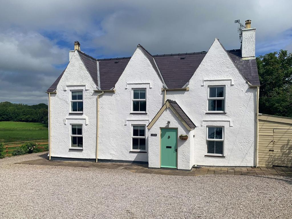 uma grande casa branca com uma porta verde em Cae Du em Llanfairpwllgwyngyll