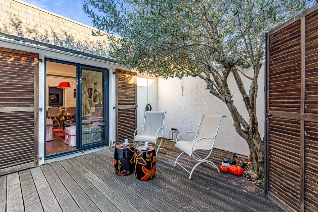 2 Stühle und ein Tisch auf einer Holzterrasse in der Unterkunft Maison Avocette - Welkeys in La Rochelle