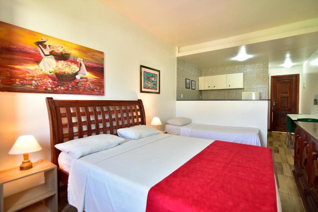 ein Schlafzimmer mit einem großen weißen Bett mit einer roten Decke in der Unterkunft FLAT Estalagem 11 in Arraial do Cabo