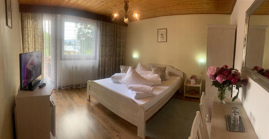 錫納亞的住宿－Vila Thomas，一间卧室配有一张床和一张鲜花桌