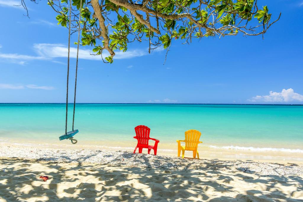 two chairs on a beach with the ocean at Sand and Tan Beach Hotel in Ocho Rios