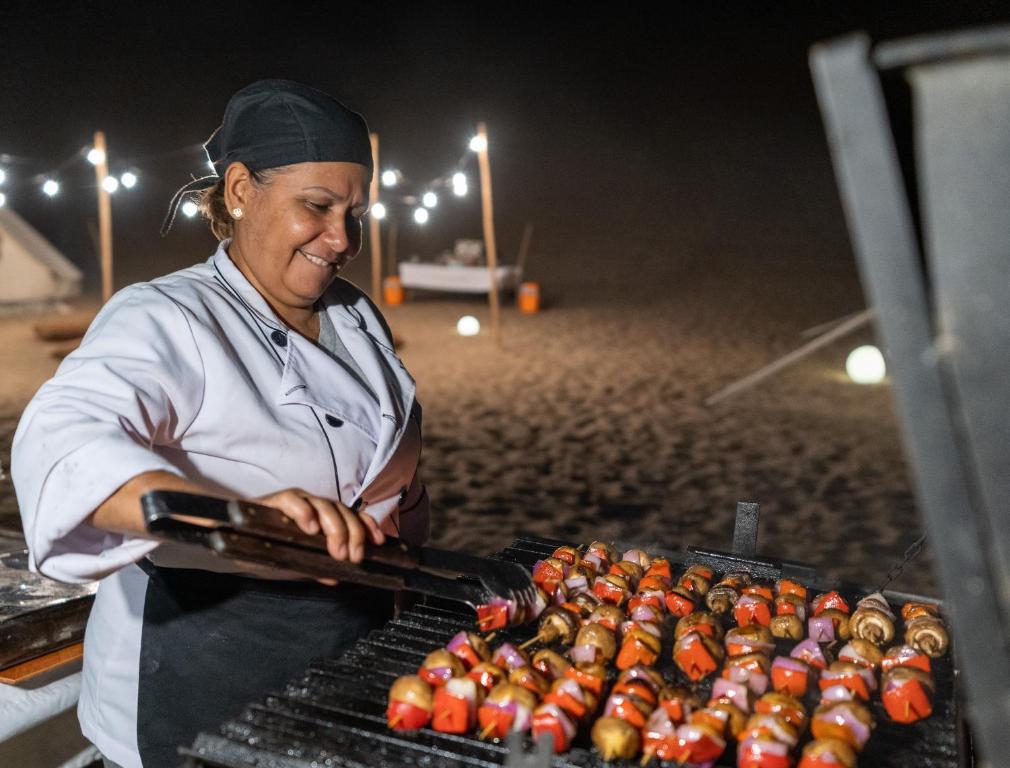 a woman is cooking food on a grill at Duna Camp Huacachina in Ica