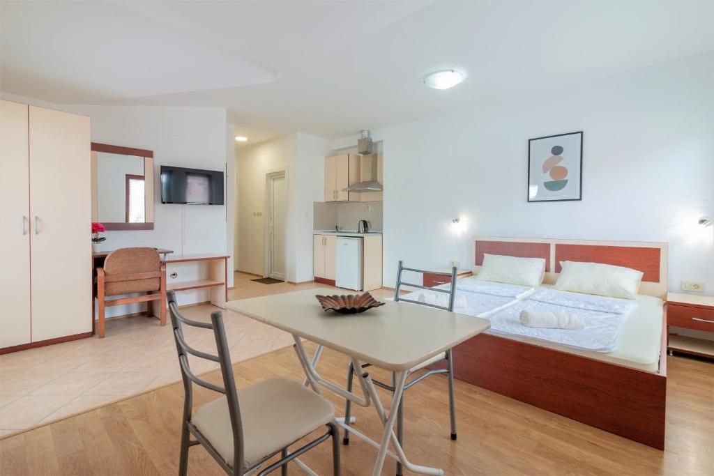 a bedroom with a bed and a table and a kitchen at Apartments Serafimoski in Ohrid