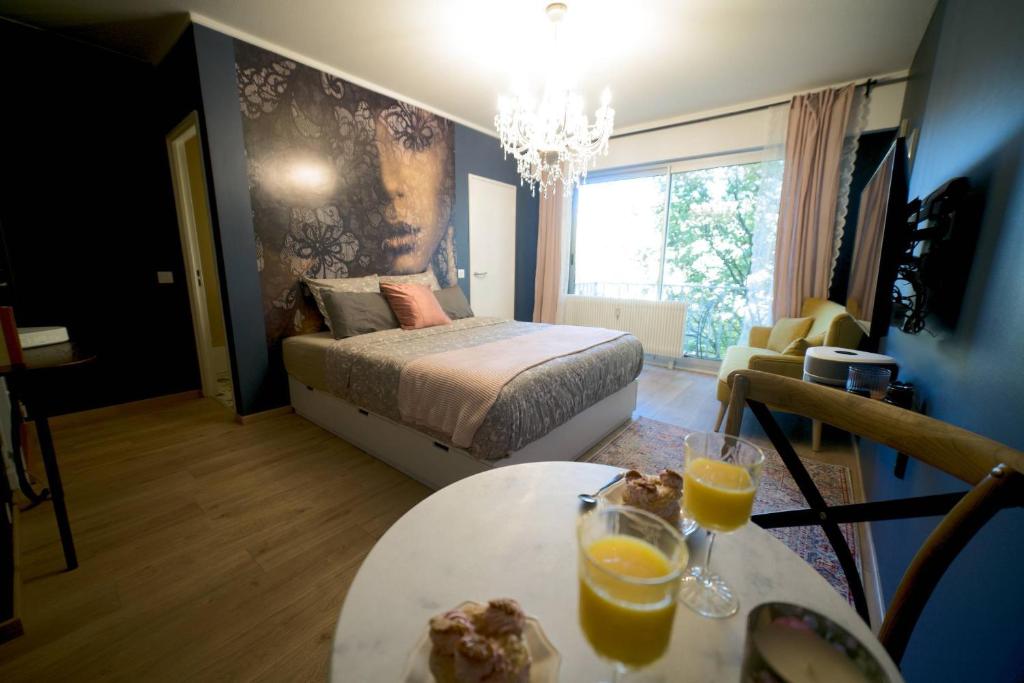 um quarto com uma cama e uma mesa com dois copos de sumo de laranja em Le Boudoir, Centre ville, Parking couvert inclus em Mulhouse