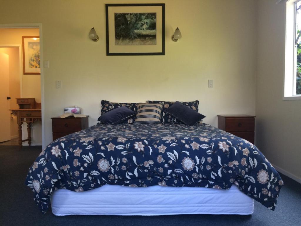 a bedroom with a bed with a blue comforter at Ohuka Lodge in Tuai