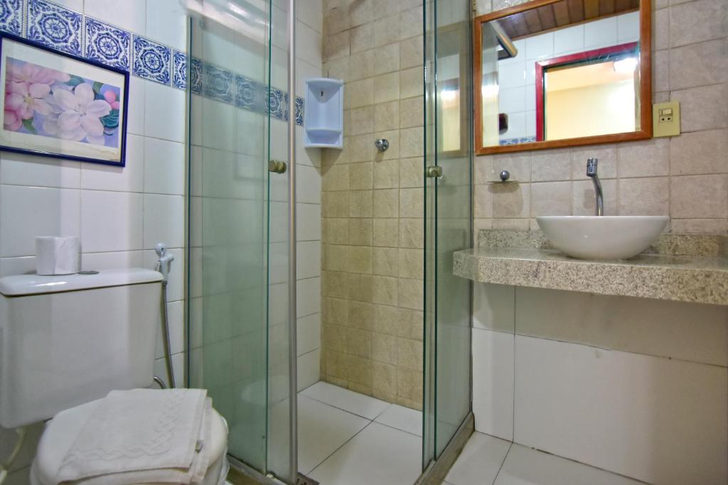 La salle de bains est pourvue d'une douche en verre et d'un lavabo. dans l'établissement Pousada Estalagem do Porto, à Arraial do Cabo