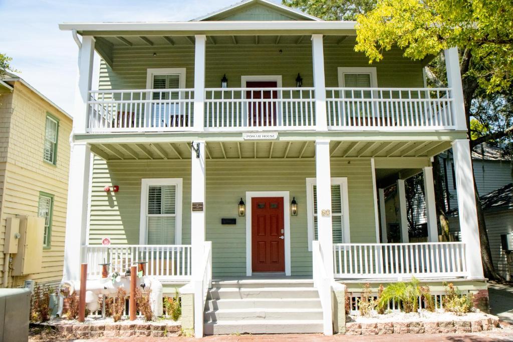 una casa verde con portico bianco e porta rossa di Pomar House a St. Augustine