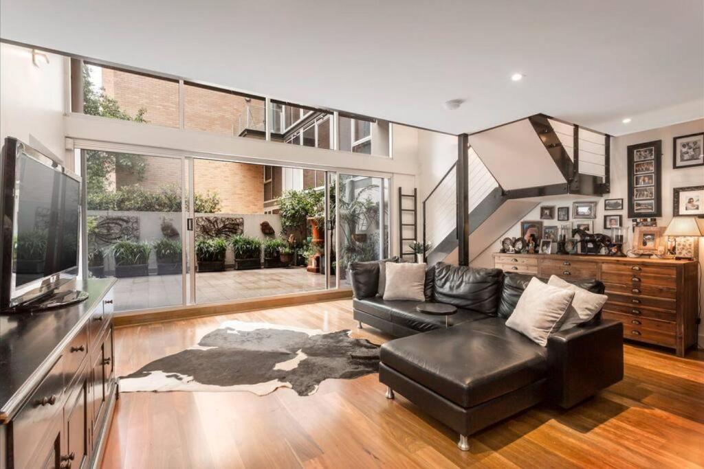 salon z czarną skórzaną kanapą i schodami w obiekcie Spacious 4 brm Gem right in the heart of the city w Melbourne