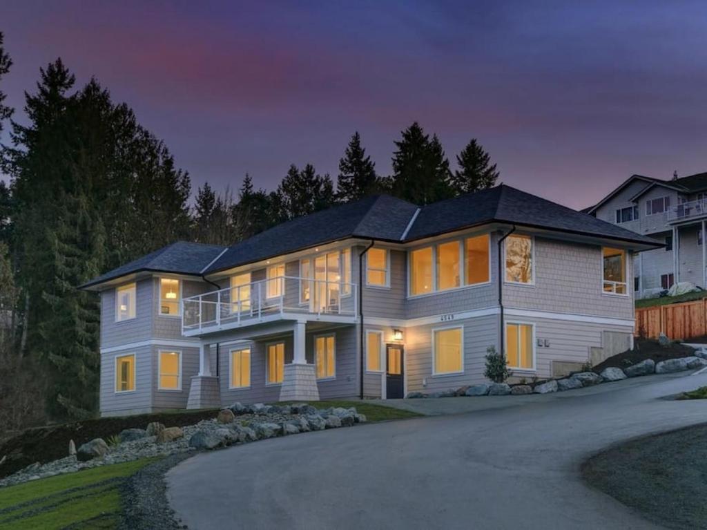 una casa grande por la noche con las luces encendidas en Big 4 Bd, 4 Ba home, Steps to Ocean with EV Charger, en Cowichan Bay