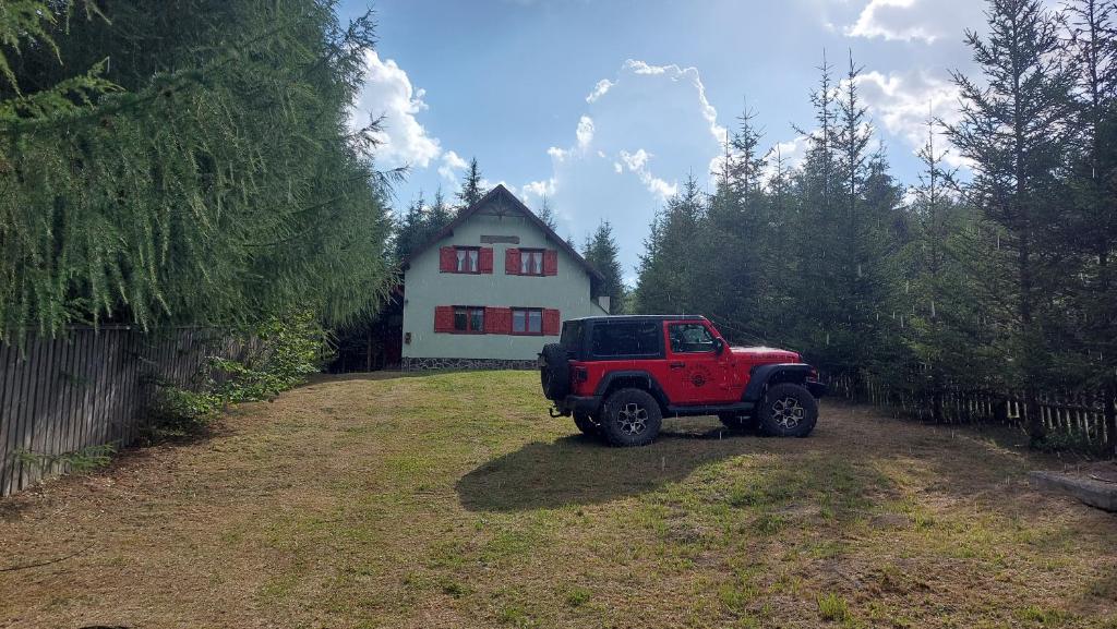 une jeep rouge garée devant une maison dans l'établissement Csalóka kulcsosház, à Harghita-Băi