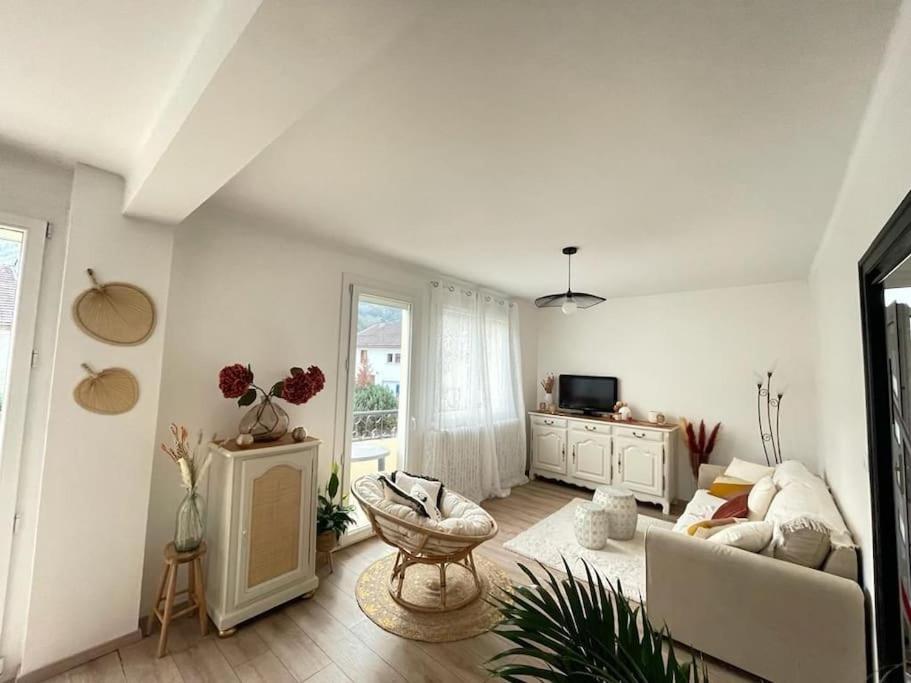 a white living room with a couch and a chair at Superbe appartement avec salle de jeux in Vaux-lès-Saint-Claude