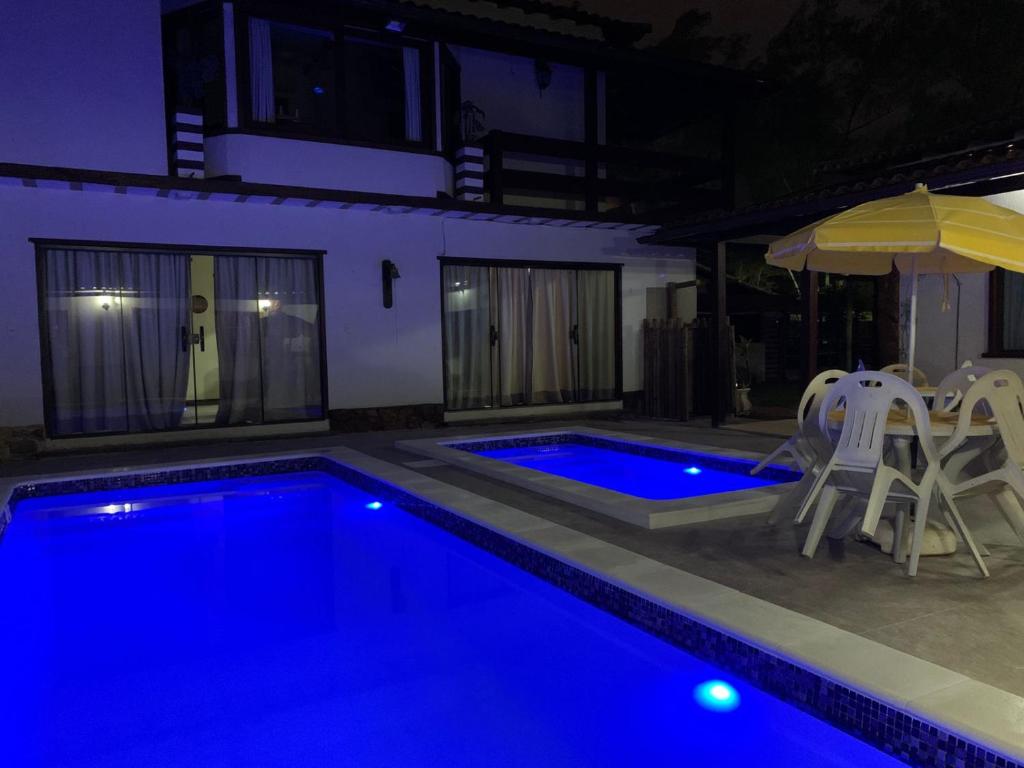 a swimming pool at night with chairs and an umbrella at Pousada Fazendinha Unamar in Cabo Frio