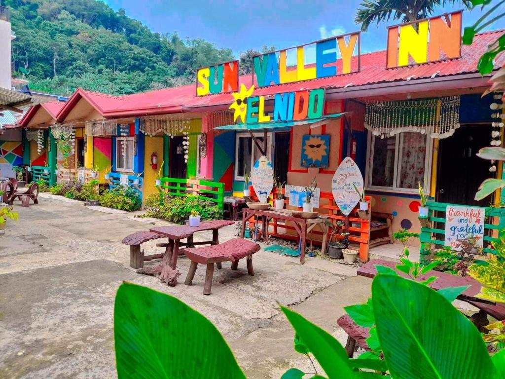 a colorful building with tables and chairs in front of it at Sun Valley Hostel in El Nido