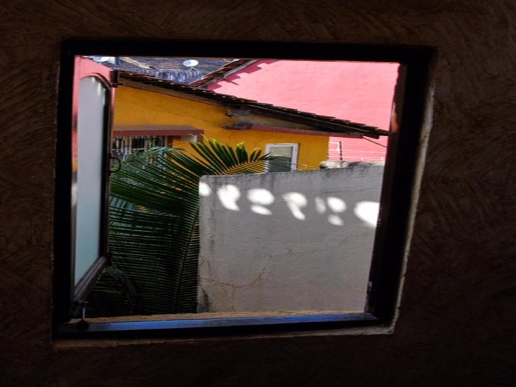 a mirror reflection of a yellow house with a fence at Afonso Guest House - Fontainhas in Panaji