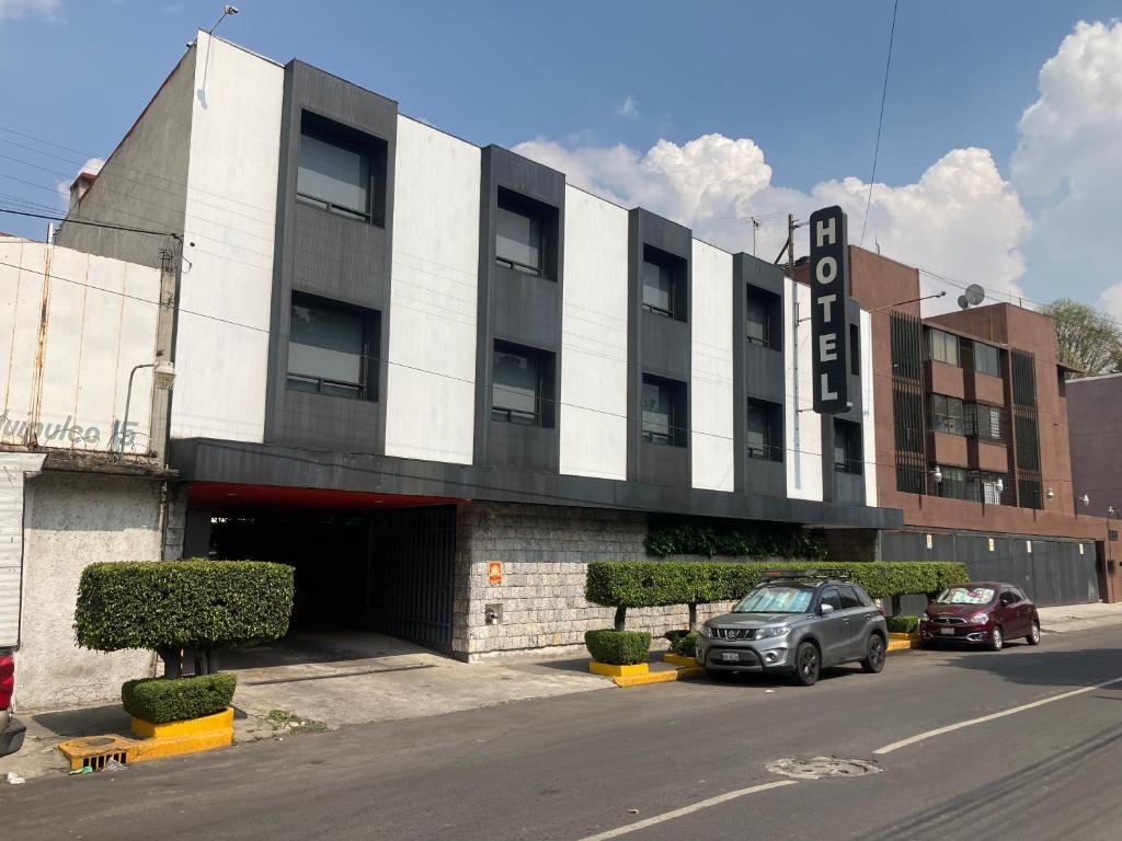 un bâtiment avec des voitures garées devant lui dans l'établissement HOTEL HUIPULCO, à Mexico