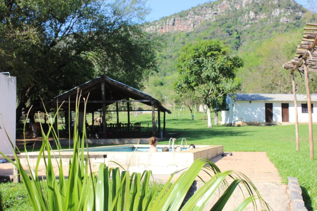 a person in a swimming pool with a house and mountains at Posada San Miguel in Paraguarí
