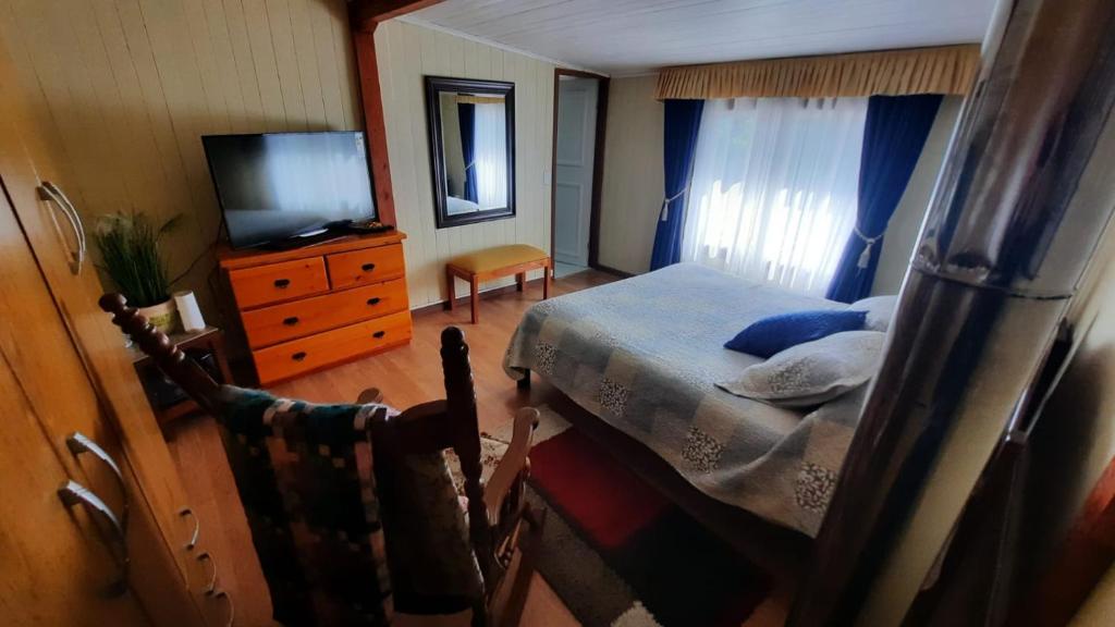 1 dormitorio con cama, TV y tocador en Hospedaje Los Tatis, en Villarrica