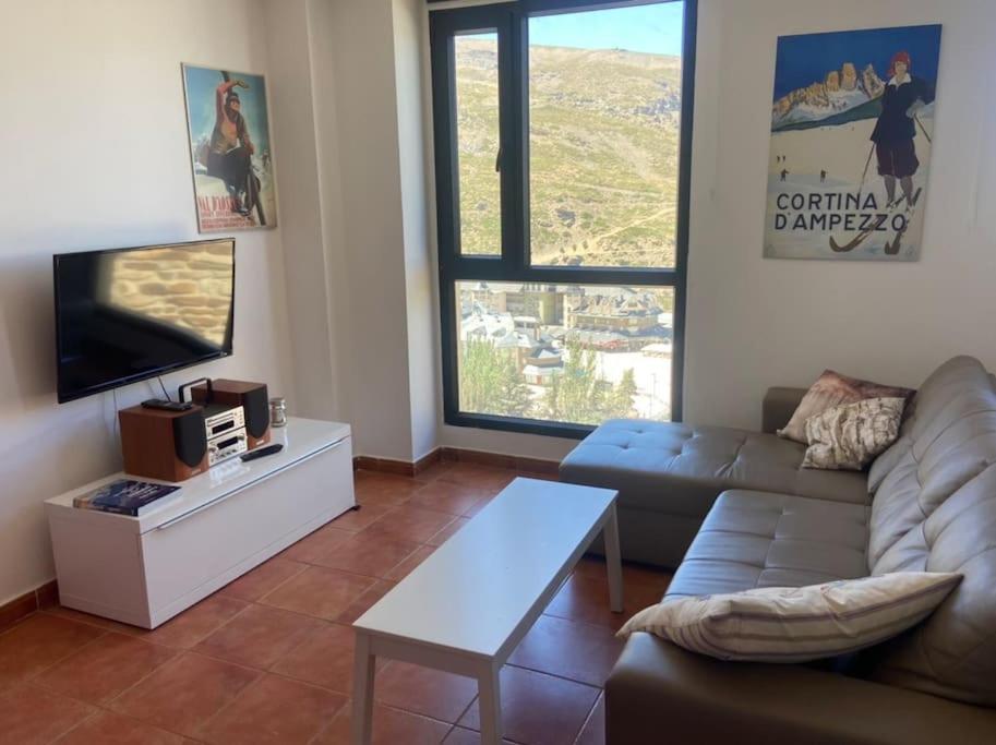 uma sala de estar com um sofá e uma televisão de ecrã plano em Ático dúplex en Monte Gorbea em Serra Nevada