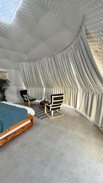 una camera da letto con tenda, letto e sedia di Starry Domes Desert Camp a Badīyah