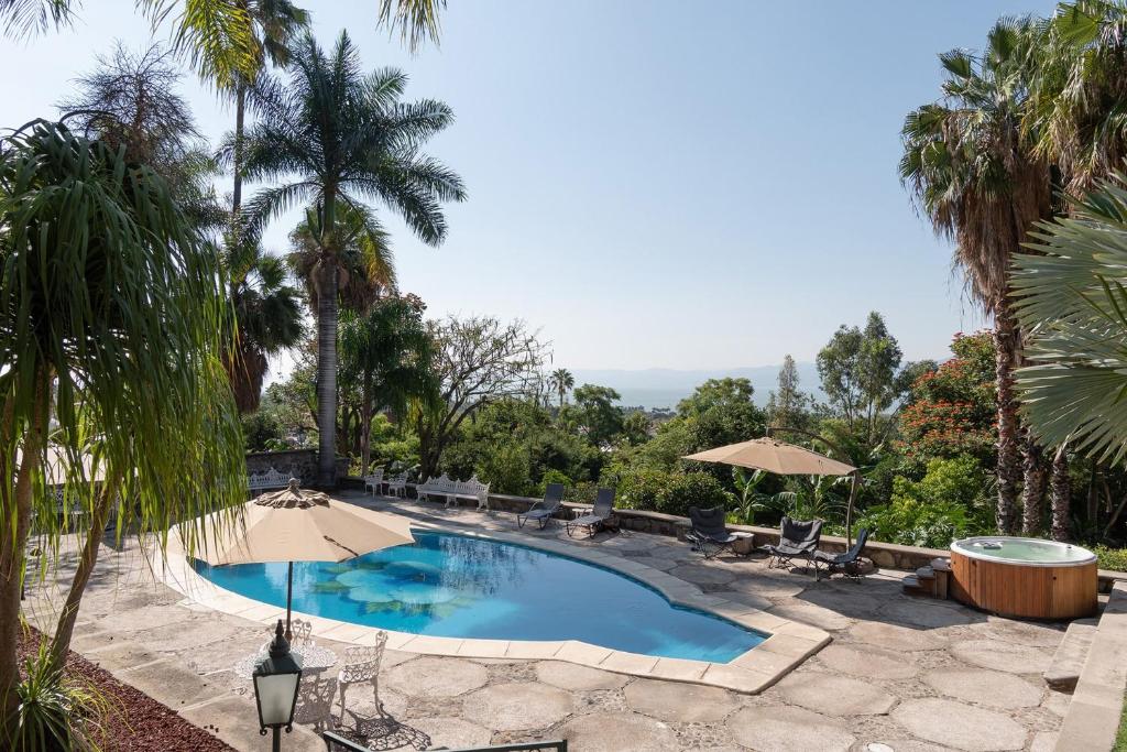 a swimming pool with chairs and umbrellas at Casa Galeana- Tropical 1-BD 1-WC Mountain Top Luxury Suite with Stunning Views in Ajijic