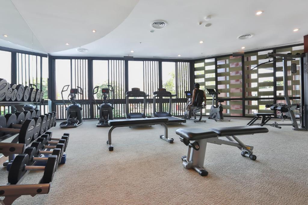 A bright fitness room with cardio machines, free weights and adjustable benches.