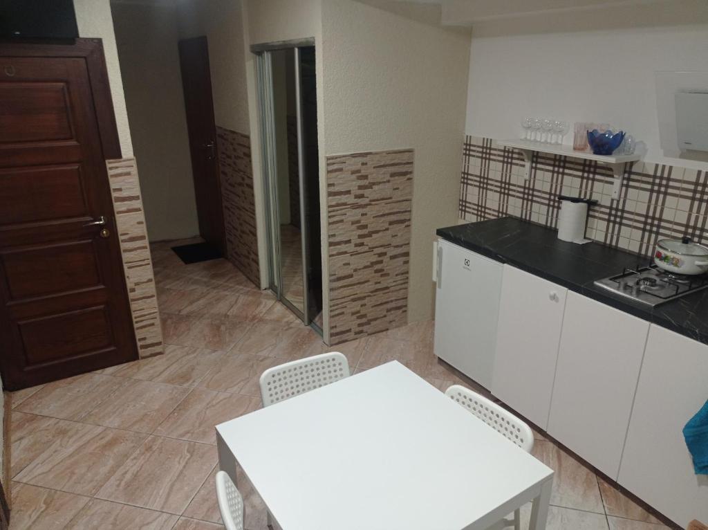 a kitchen with white cabinets and a white table and chairs at Apartment parking loft Akaciju in Vilnius