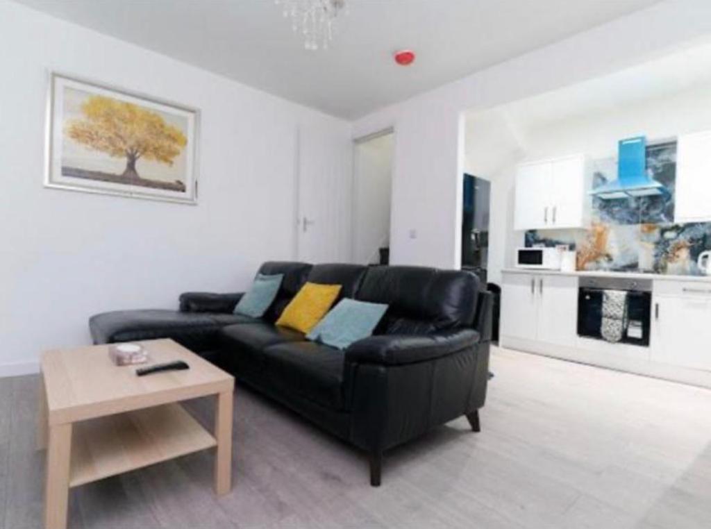 a living room with a black couch and a table at Bayswater Apartments with Free Parking in Leeds