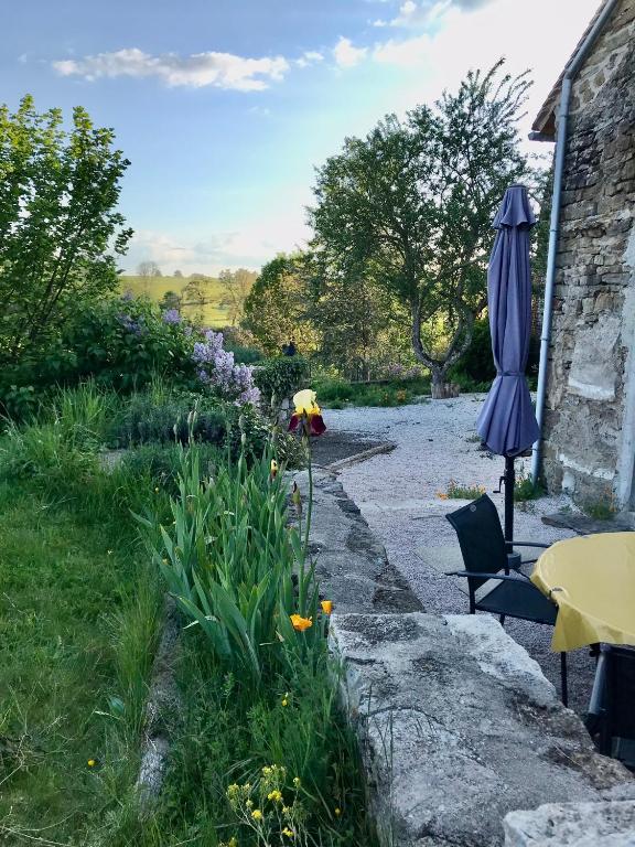 un parasol installé à côté d'un jardin fleuri dans l'établissement Gîte de la Pisserotte, à Montigny-sur-Armançon