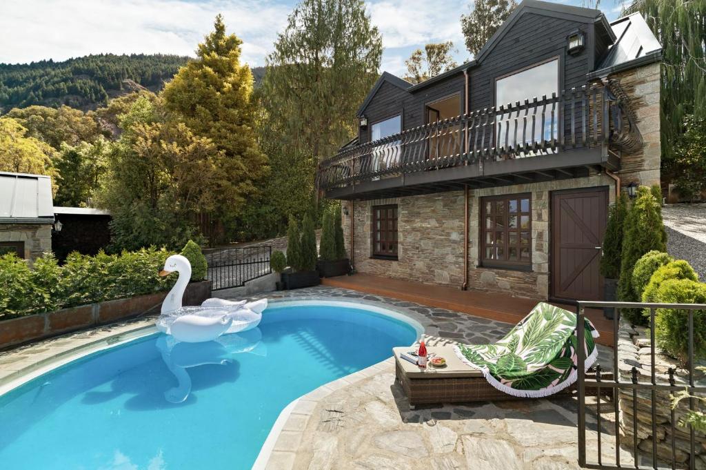 a swimming pool in front of a house with a swan at Alpine Cottage in Queenstown