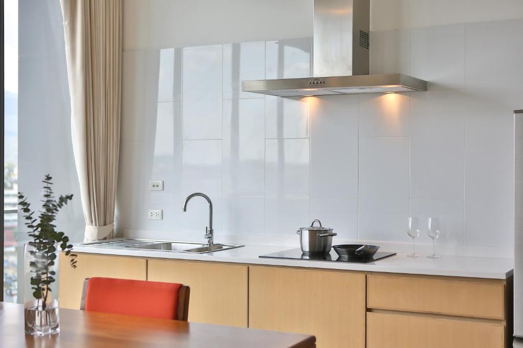 A light-filled kitchenette with a sink, cooktop hood and dining table.