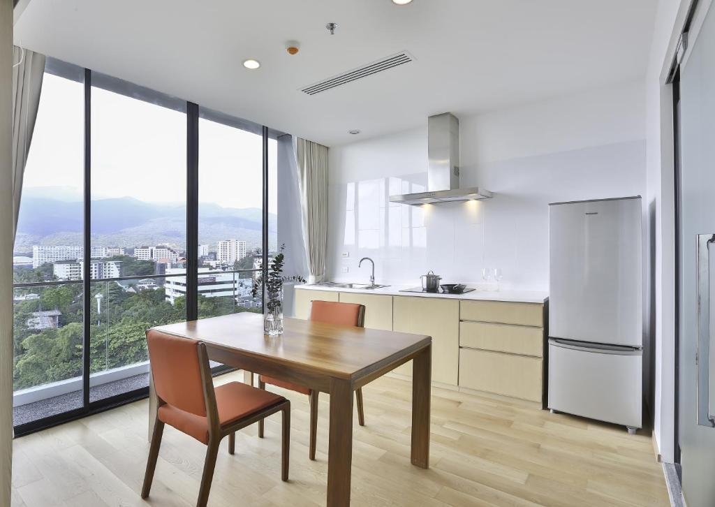 A compact apartment-style kitchen has a dining table for two and expansive windows overlooking the city and hills.