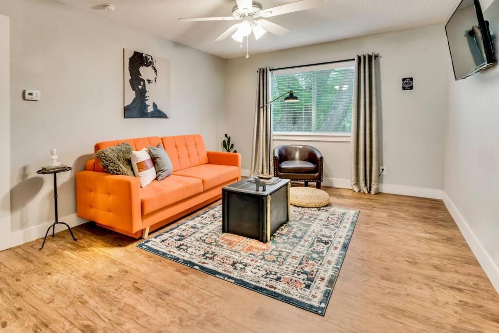 a living room with an orange couch and a table at Love for Dallas: Close to Deep Ellum & AAC! in Dallas