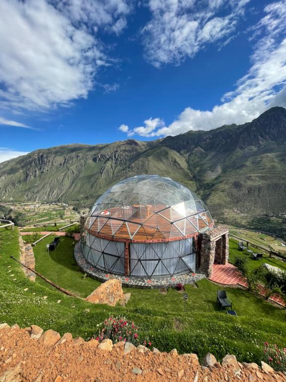 een glazen koepel op een heuvel met bergen op de achtergrond bij StarDomeLodge in Ollantaytambo