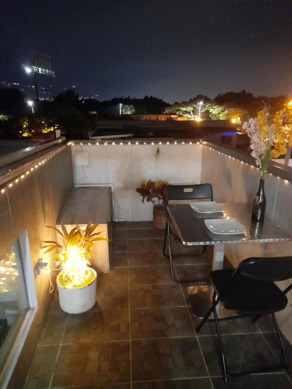 un patio en la azotea por la noche con mesa y sillas en apartaestudio terraza Romantico #14, en Cali
