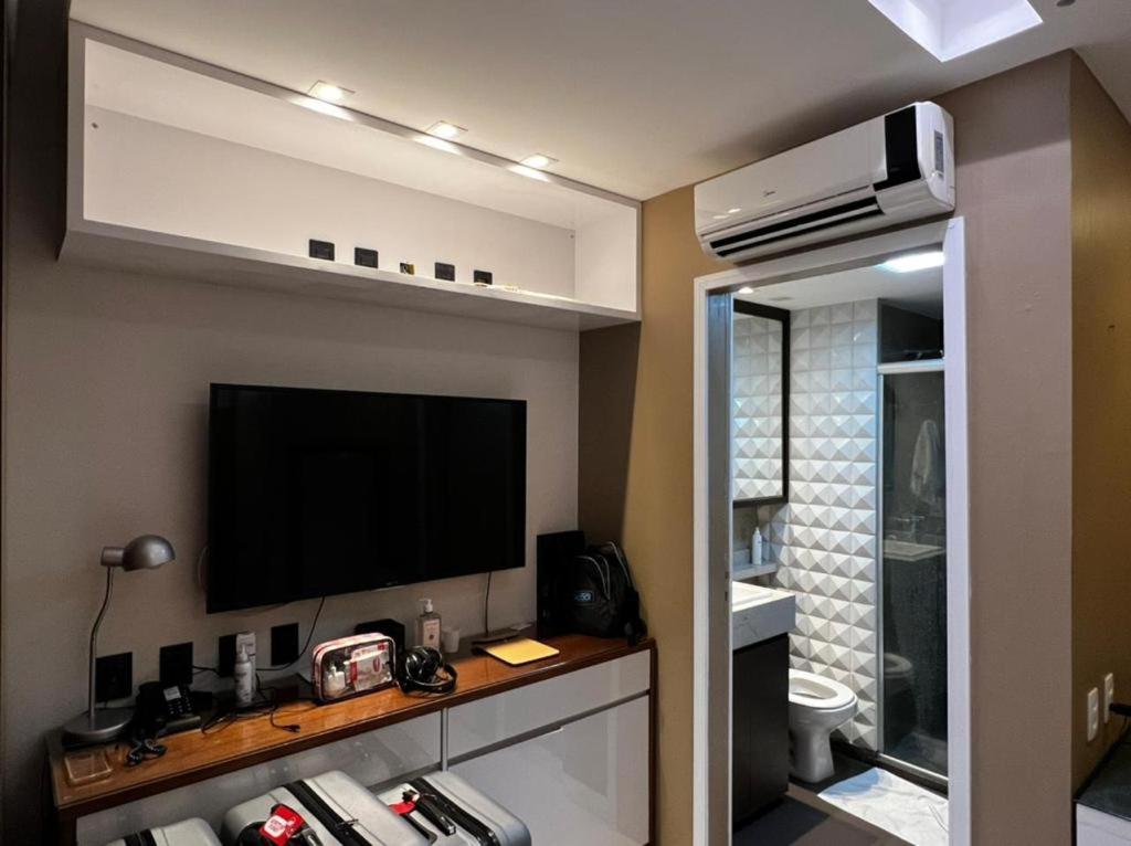 a living room with a television and a bathroom at Flat Setor de Hotéis Norte no Hotel Fusion in Brasilia