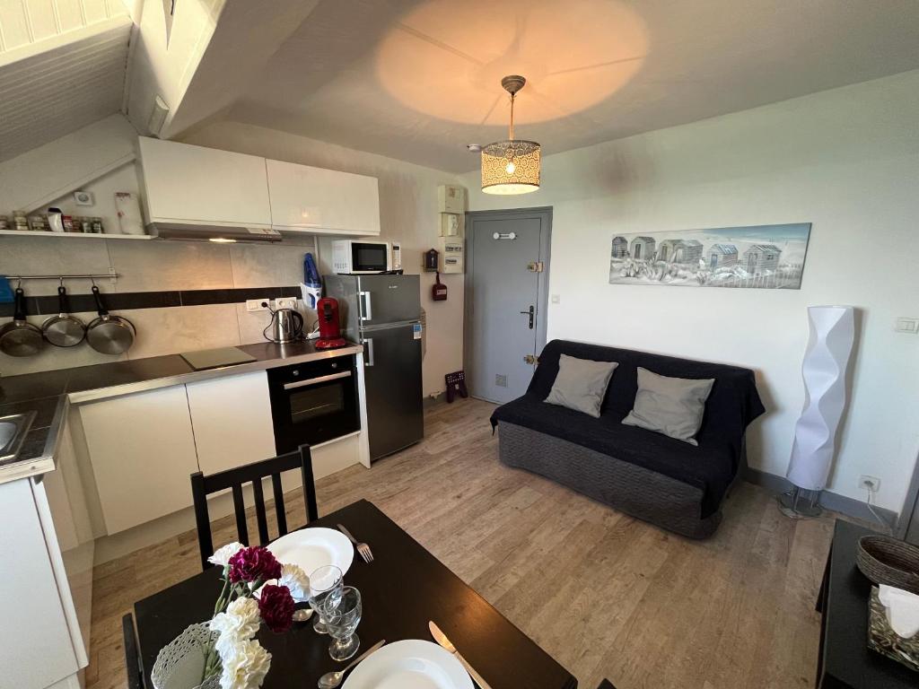 uma cozinha e uma sala de estar com um sofá e uma mesa em Acrab YourHostHelper em Luc-sur-Mer