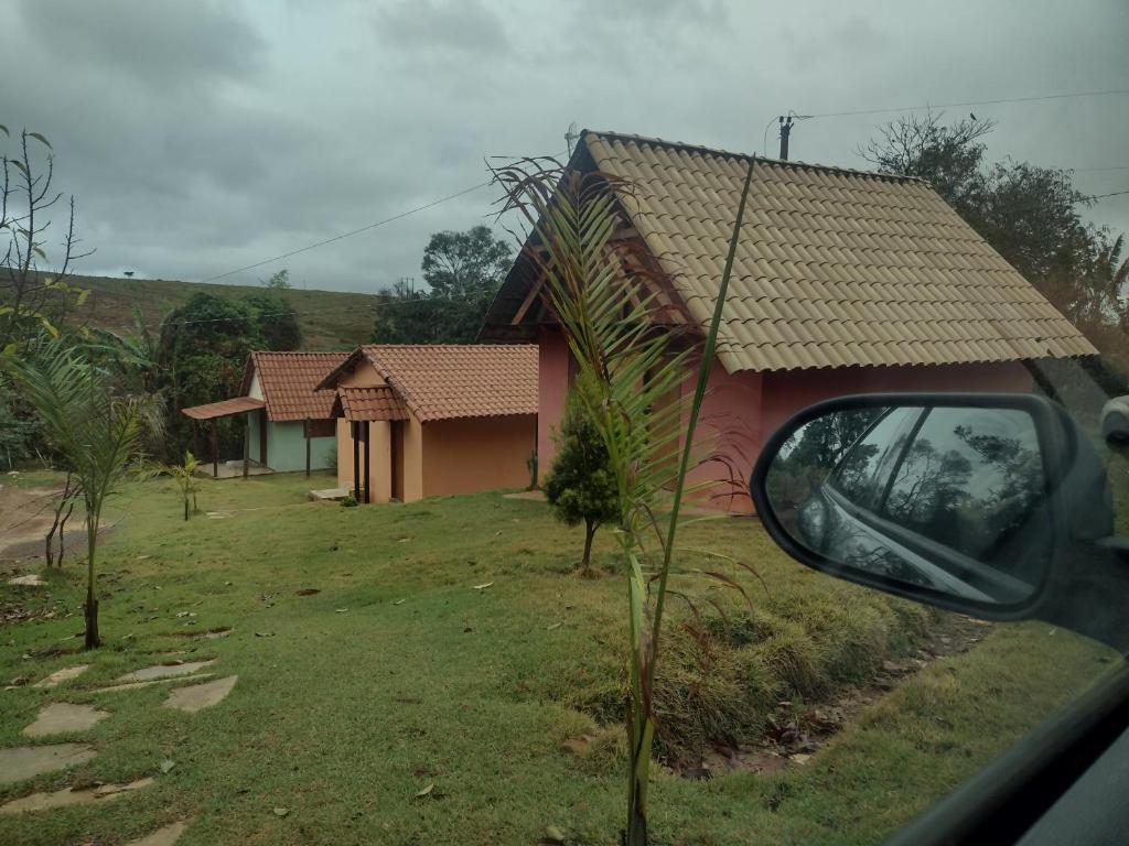 una vista di una casa dallo specchietto retrovisore laterale di un'auto di SITIO CAMINHO DAS PEDRAS - Suítes e Chalés a São Thomé das Letras