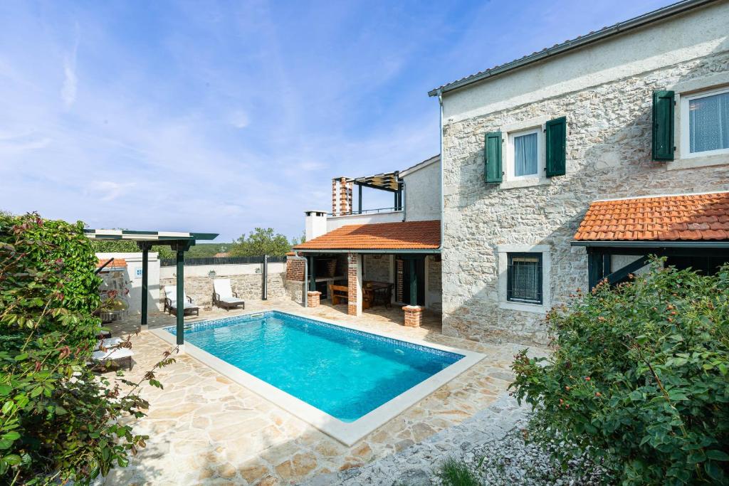 una piscina frente a una casa de piedra en Villa MiA, en Sukošan