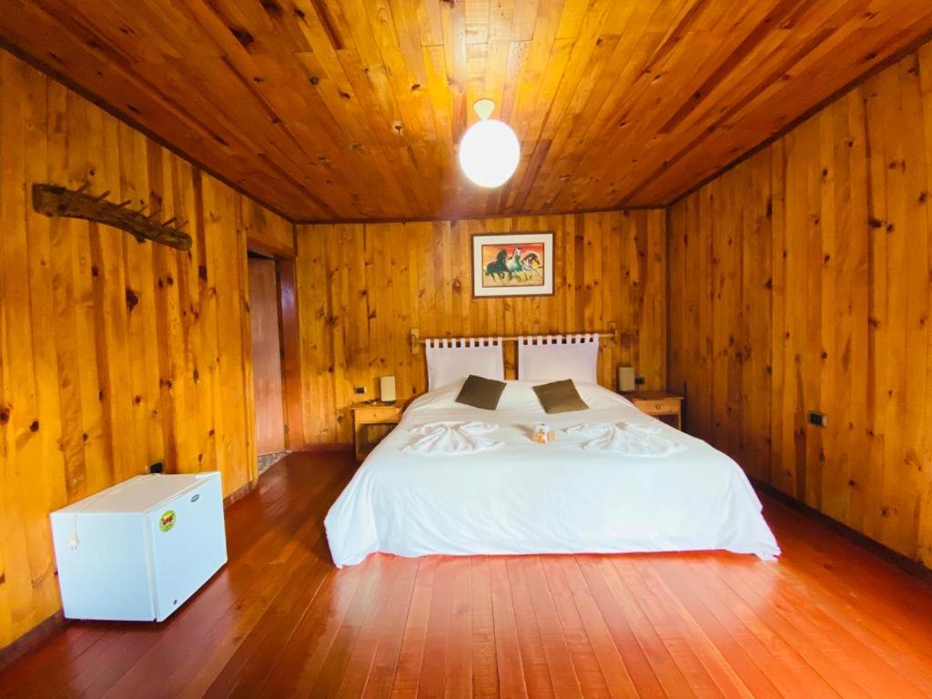 a bedroom with a white bed in a wooden room at Cabañas Palma Sky Lodge in Oxapampa