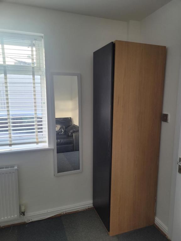 a room with a mirror and a cabinet and a window at No 5 Decent Homes ( Luxury Extra-large bedroom) in Ashton under Lyne
