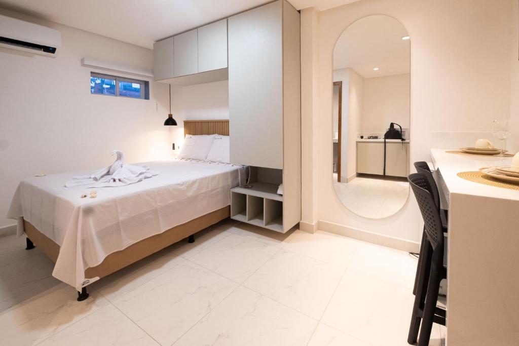 1 dormitorio con cama blanca y espejo en Pé na Vila, en Porto de Galinhas