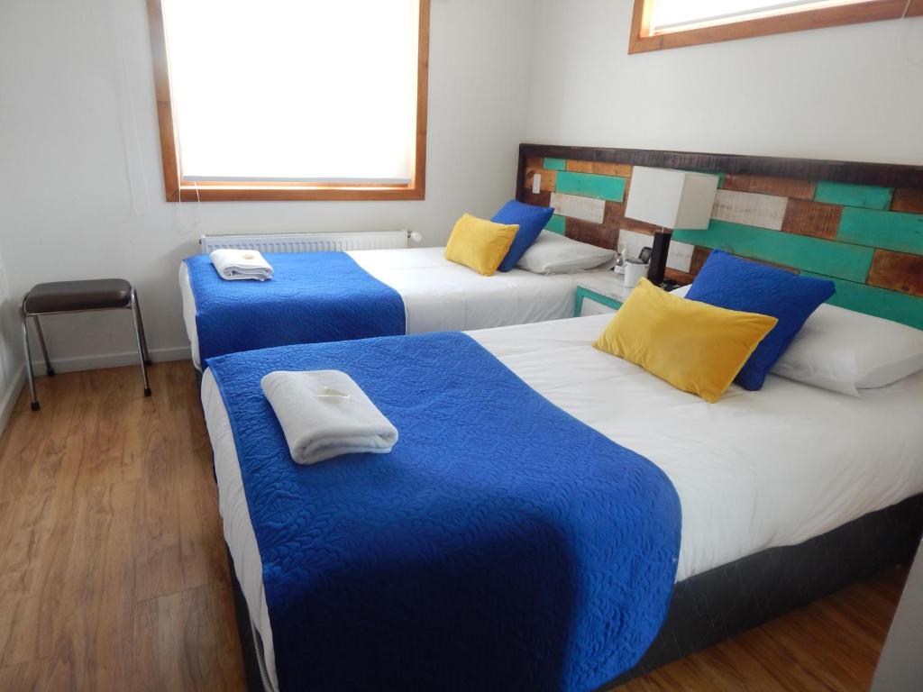 a room with three beds with blue and yellow pillows at Hostal Buenavista Patagonia in Punta Arenas