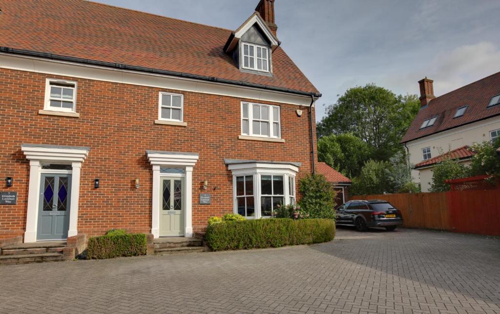 une maison en briques avec une voiture garée dans l'allée dans l'établissement Elizabeth Townhouse Braintree, 