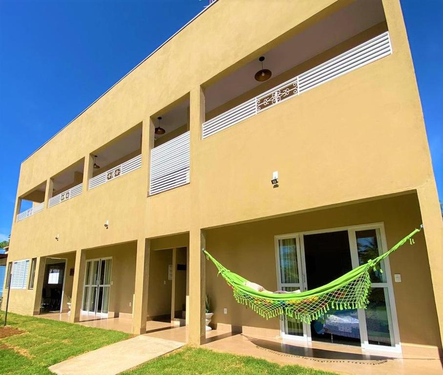 un edificio con una hamaca verde delante de él en Pousada La Belle de Jour en Chapada dos Guimarães