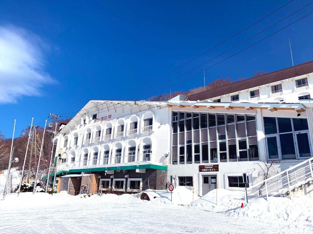 a large white building with snow in front of it at Shiga Swiss Inn in Yamanouchi